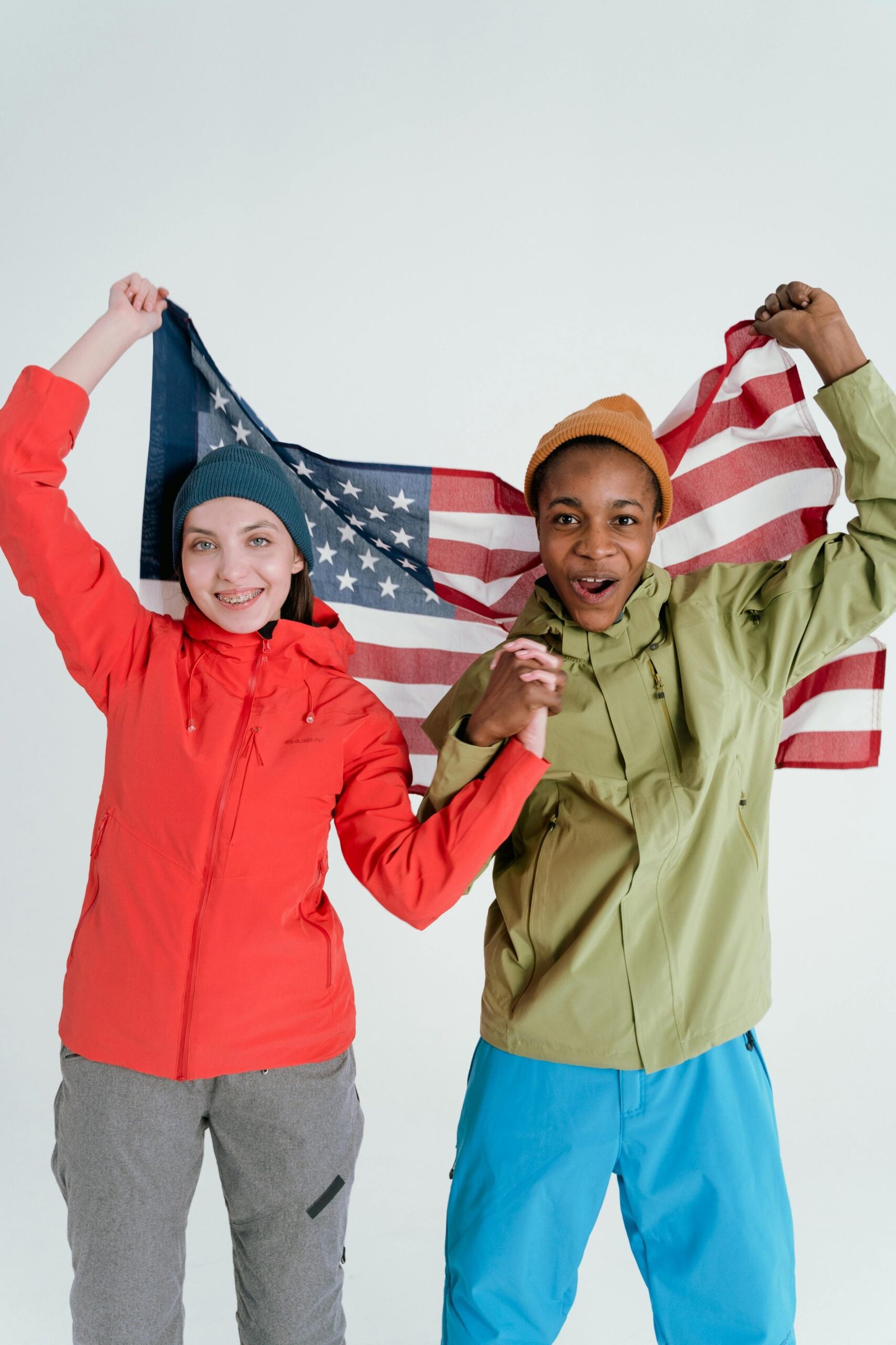 African American and Caucasian friends holding the USA flag in joyful celebration.